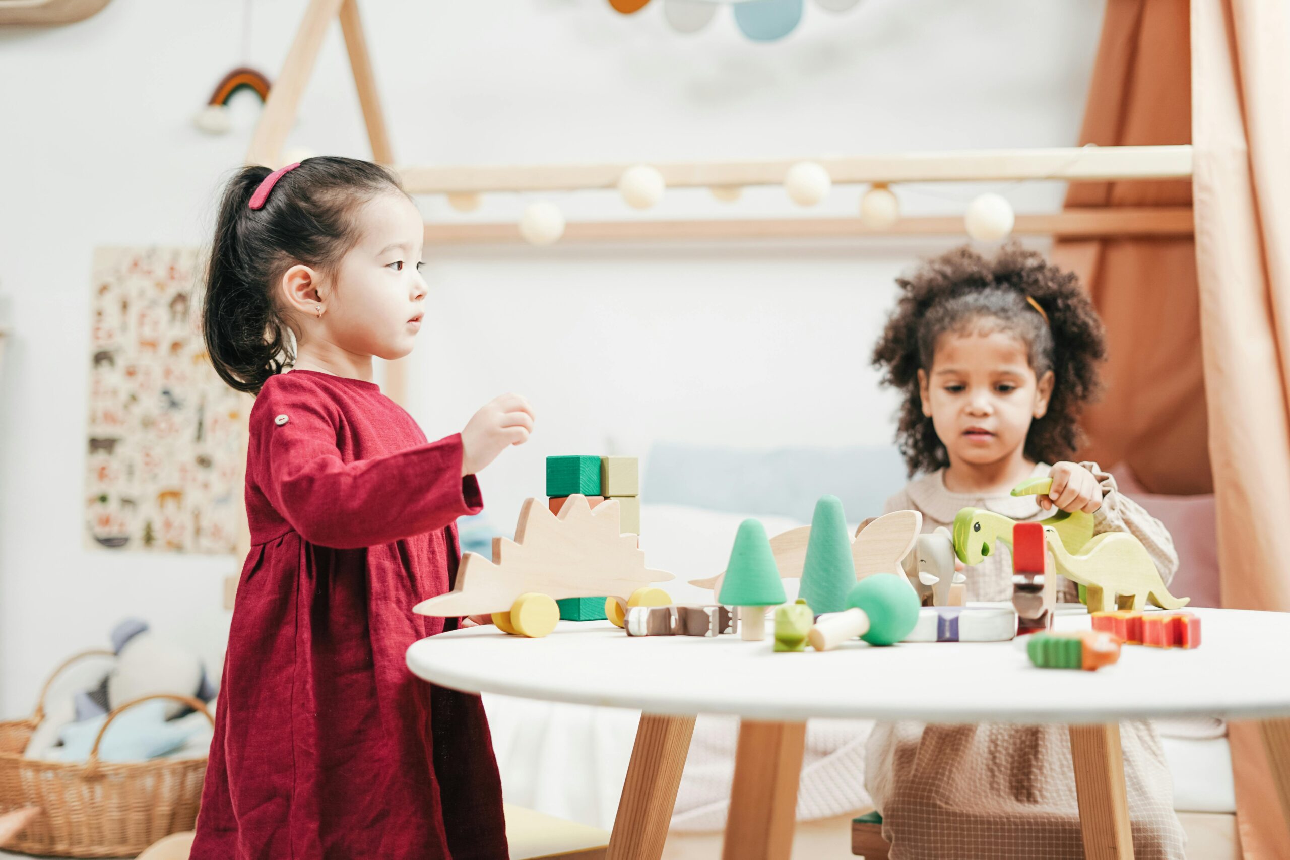 Two children engaging with wooden toys in a bright playroom. Ideal for education themes.